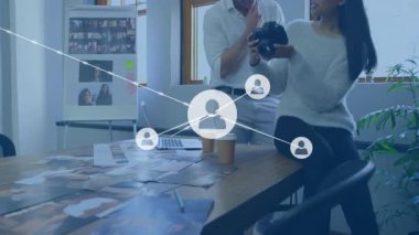 İş arkadaşı kamera kontrollerini işaret ederek ağ düğümlerini başlatarak fotoğrafları görselleştiriyor. Yaratıcı takım çalışması, dijital işbirliği, ağ oluşturma, iletişim, yenilik, modern çalışma alanı, görsel hikaye anlatma