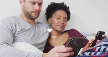 Adam kanepede tablet kaydırıyor ve kadın akıllı telefon kullanıyor. Kalpleri gözüken teknoloji bağlarını paylaşıyor. Romantizm, samimiyet, bağlantı, rahatlama, sıcak, sevecen, modern