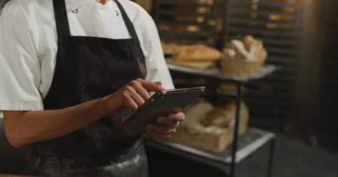 Tablet kullanan Asyalı fırıncının orta bölümünün animasyonu. Pastanede çalışmak, bağımsız küçük işletme.