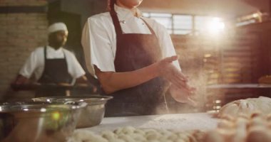 Mutlu Asyalı fırıncı kadın un temizlemek için el çırpıyor. Pastanede çalışmak, bağımsız küçük işletme.