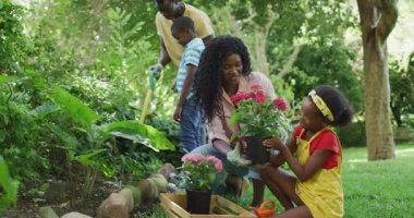 Mutlu Afro-Amerikan ailesinin bahçede birlikte çiçek dikmesinin animasyonu. Aile, bahçıvanlık, birlikte dışarıda kaliteli zaman geçirmek..