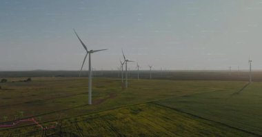 Rüzgar türbinlerinin üzerinde yeşil çizgi çizelgesi beliriyor ve şamdanlar enerji eğilimlerini gösteriyor. Yenilenebilir enerji, sürdürülebilirlik, çevre, teknoloji, temiz güç, altyapı, veri görselleştirme