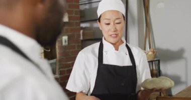 Asyalı kadın fırıncının iş arkadaşına nasıl ekmek yapılacağını açıklarken canlandırması. Pastanede çalışmak, bağımsız küçük işletme.