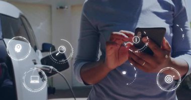 Akıllı telefonu dinleyen ve elektrik kablosunu EV 'ye bağlarken teknoloji simgelerini ortaya çıkaran bir kadın. Teknoloji, yenilik, sürdürülebilirlik, bağlantı, modern, çevre dostu, dijital