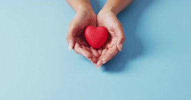 Mavi arka planda kalbi tutan beyaz bir kadının elleri. tıp, sağlık, kanser farkındalığı konsepti dijital olarak üretilen video.