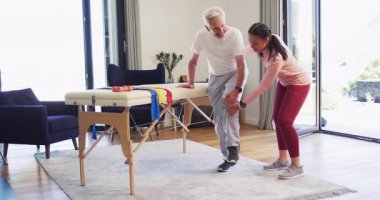 Kafkas kıdemli bir adamla egzersiz yapan mutlu kadın fizyoterapistin videosu. Yaşlılar sağlığı ve huzurevi konsepti dijital olarak oluşturulmuş video.