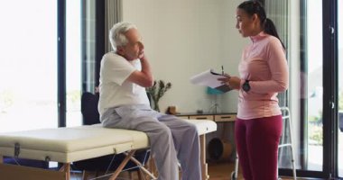 Kadın fizyoterapistin Kafkasyalı yaşlı adamı muayene ettiği video. Yaşlılar sağlığı ve huzurevi konsepti dijital olarak oluşturulmuş video.
