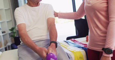 Kafkas kıdemli bir adamla egzersiz yapan mutlu kadın fizyoterapistin videosu. Yaşlılar sağlığı ve huzurevi konsepti dijital olarak oluşturulmuş video.