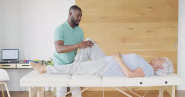 Afrika kökenli Amerikalı erkek fizyoterapistin beyaz yaşlı kadınla egzersiz yaptığı bir video. Yaşlılar sağlığı ve huzurevi konsepti dijital olarak oluşturulmuş video.