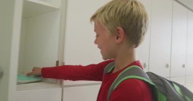 Dolabı kapatıp okulda gülümseyen beyaz bir çocuğun videosu. ilköğretim, bilgi ve öğrenme kavramı.