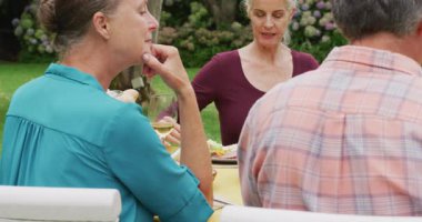 Arkadaşlarıyla bahçede öğle yemeği yiyen Kafkasyalı son sınıf mutlu kadının animasyonu. Emeklilik yaşam tarzı, arkadaşlarla kaliteli zaman geçirme.