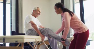 Kadın fizyoterapistin Kafkasyalı yaşlı adamı muayene ettiği video. Yaşlılar sağlığı ve huzurevi konsepti dijital olarak oluşturulmuş video.