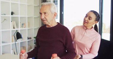 Kafkas kıdemli bir adamla egzersiz yapan mutlu kadın fizyoterapistin videosu. Yaşlılar sağlığı ve huzurevi konsepti dijital olarak oluşturulmuş video.