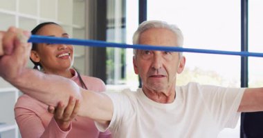 Kafkas kıdemli bir adamla egzersiz yapan mutlu kadın fizyoterapistin videosu. Yaşlılar sağlığı ve huzurevi konsepti dijital olarak oluşturulmuş video.