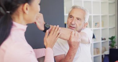 Kafkas kıdemli bir adamla egzersiz yapan mutlu kadın fizyoterapistin videosu. Yaşlılar sağlığı ve huzurevi konsepti dijital olarak oluşturulmuş video.