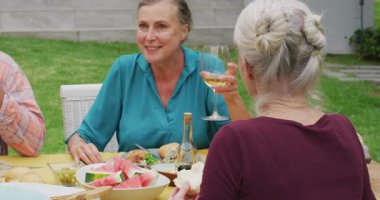 Arkadaşlarıyla bahçede öğle yemeği yiyen Kafkasyalı son sınıf mutlu kadının animasyonu. Emeklilik yaşam tarzı, arkadaşlarla kaliteli zaman geçirme.