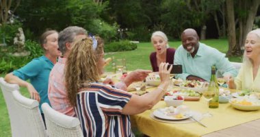 Çeşitli mutlu son sınıf kız ve erkek arkadaşlarının akıllı telefon kullanarak bahçede öğle yemeği yediği animasyon. Emeklilik yaşam tarzı, arkadaşlarla kaliteli zaman geçirme.