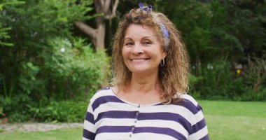 Bahçede kameraya gülümseyen yaşlı kadın animasyonu. Emeklilik hayatı, dışarıda boş zaman geçirmek..