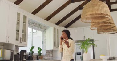 Afro-Amerikan kadının mutfakta akıllı telefon kullandığı bir video. ev ofisi ve online çalışma konsepti.