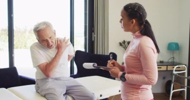 Kadın fizyoterapistin Kafkasyalı yaşlı adamı muayene ettiği video. Yaşlılar sağlığı ve huzurevi konsepti dijital olarak oluşturulmuş video.