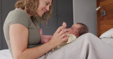 Yeni doğmuş bebekle oynayan mutlu beyaz bir annenin videosu. annelik, ebeveyn sevgisi ve yeni doğan bebek konseptiyle ilgilenmek dijital olarak üretilmiş video.