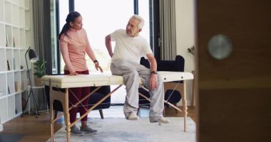 Kadın fizyoterapistin Kafkasyalı yaşlı adamı muayene ettiği video. Yaşlılar sağlığı ve huzurevi konsepti dijital olarak oluşturulmuş video.