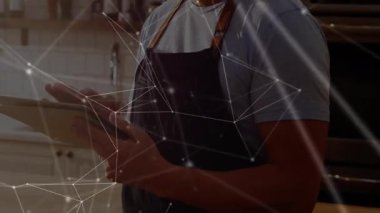 Erkek aşçı tablet ekranı tıklatıyor ve mutfak alanına danışarak ağ kaplamasını etkinleştiriyor. Teknoloji, yenilik, aşçılık, gurme, modern, profesyonel, bağlantı