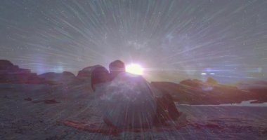 Güneş batışı, kayalık sahildeki çift etrafında ışık demetleri ve yıldızlarla teknolojinin örtüşmesine neden oluyor. Romantik, dinginlik, kozmik, alacakaranlık, ufuk, siluet, sükunet