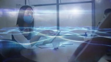 Maskeli kadın, iş brifinginde iş arkadaşına tablet veriyor ve el sallıyor. İşbirliği, iletişim, teknoloji, profesyonellik, işyeri, dijital, etkileşim