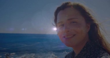 Vlogger kameraya gülümsüyor, güneş denizde parlıyor mercek parlıyor, yıldız patlaması başlıyor, bakışlar kayıyor. Manzara, güzellik, sükunet, macera, doğal, parlayan, açık hava