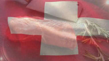 İşviçre bayrağı çiğ et üzerinde beliriyor ve dalgalanıyor sonra da satırı, biberiyeyi ortaya çıkarmak için soluyor. Mutfak, kasaplık, hazırlık, köy, tazelik, mutfak, işçilik