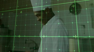 Aşçı tableti kaldırıyor ve yeşil ızgara mutfak operasyonlarını yönetirken yemek tariflerini tarıyor. Mutfak, yenilik, teknoloji, modern, profesyonel, iş akışı, gösterge paneli