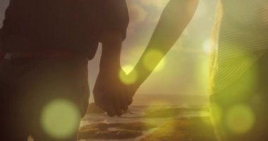 Güneş ufkun altına batarken çift seyahat için kıyı şeridi boyunca adım atarken bokeh patlamalarına neden oluyor. Romantizm, siluet, sükunet, manzara, uyum, doğa, sükunet