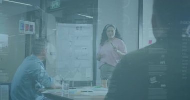 Meslektaşı soru sorarken orta yaşlı bir kadın işaretleyici seçiyor ve pazar verilerini tabloda sunuyor. Profesyonel, işbirliği, sunum, veri görselleştirme, kurumsal, modern, takım çalışması