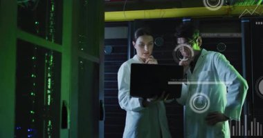 Kadın teknisyen, meslektaşı sunucu raflarını incelerken bilgisayarda veri kaydırıyor. Teknoloji, analitik, yenilik, profesyonel, dijital, fütüristik, işbirliği