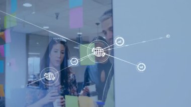 Çalışanlar iş toplantılarında yapışkan notları inceleyerek dünya ve grafik simgelerinin örtüşmesine yol açtılar. İşbirliği, yenilik, takım çalışması, veri görselleştirme, dijital bağlantı, modern çalışma alanı, beyin fırtınası