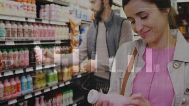 Kadın perakende reyonunda pembe içecek seçiyor ve erkeğin şişeyi sepsiyona koyduğunu okuyor. Perakende, alışveriş, koridor, içecekler, ikili, tüketici, renkli