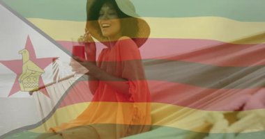 Akıllı telefonları kaydıran, okyanusa bakan pembe içkileri yudumlayan ve sahilde gülen bir kadın. Yaz, tatil, dinlenme, güneşlenme, tatil, deniz kenarı, mutluluk.