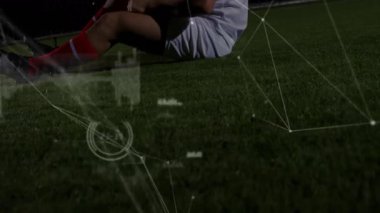 Futbolcu yaralı dizini kavrayıp cenin pozisyonuna kıvrılarak titreşimli veri aktarıyor. Sporcu, spor giyim, maç, aksiyon, stadyum, dayanıklılık, teknoloji