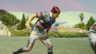 Lider rugby oyuncusu çim sahasında topu tutuyor, takım arkadaşı spor talimi için koşuyor ve iyileşiyor. Atletizm, takım çalışması, rekabet, hareket, aktif, açık hava, enerjik