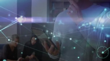 Adam akıllı telefonu dinlerken ve ağ kaplamasını etkinleştirirken ofisteki tableti gözden geçiriyordu. Teknoloji, işbirliği, dijital, yenilik, modern, iş, bağlantı