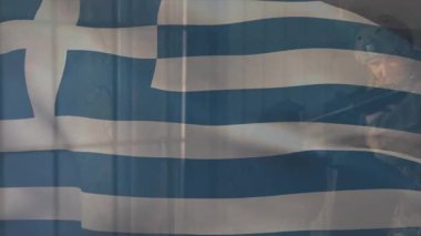 Yunan bayrak çizgileri dalgalanıyor, asker tüfeğini kaldırıyor ve savunma için pencereden içeri nişan alıyor. Ordu, savunma, kamuflaj, disiplin, dayanıklılık, takım çalışması, vatanseverlik.