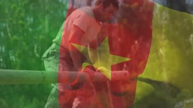 Yetişkin bir erkek, kamerun bayrağı altında eğitim parkuruna doğru sürükleniyor. Macera, açık hava, fitness, azim, dayanıklılık, doğal, dayanıklılık