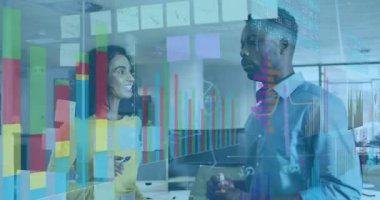 Kadın, iş verilerini vurgulamak için yapışkan notları kaldırırken, erkek de cam tahtaya çubuk grafiği not ediyor. İşbirliği, takım çalışması, analiz, veri, sunum, beyin fırtınası, şirket