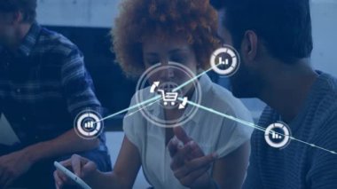 Kadın tableti tıklatıyor ve ekip veri takibi yaparken alışveriş arabasının ikonları teknoloji toplantısına bağlanıyor. İşbirliği, takım çalışması, veri analizi, modernlik, dijital ağ, iş toplantısı, profesyonel gelişim