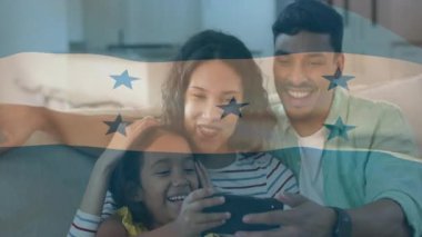 Baba akıllı telefon ekranını dinliyor ve anne kızını destekliyor kanepe bağlanmasında teknoloji uygulamasını keşfediyor. Aile, bağ, teknoloji, eğlence, ev, bağlantı, mutluluk