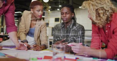 Orta yaşlı bir adam çizimlere el koyuyor, tasarım ekibi renkli işaretli yerleri gözden geçiriyor. İşbirliği, takım çalışması, yenilik, beyin fırtınası, yaratıcılık, ofis, tartışma