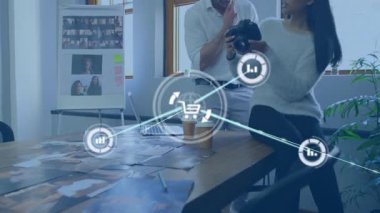 Erkek kamerayı kadın kontrolleri çeviriyor, çalışma alanındaki animasyon analitik simgeleri ortaya çıkarıyor. Yaratıcı, takım çalışması, yenilik, teknoloji, analitik, dijital, çalışma alanı