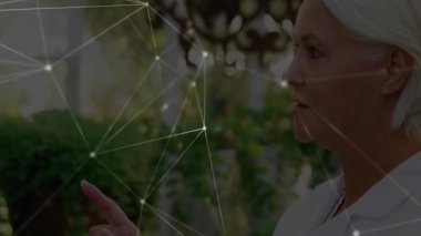 Kıdemli kadın serada parmak kaldırarak hareket kontrol düğümlerini gösteriyor. Fütüristik, bağlantı, yenilik, teknoloji, botanik, dalgın, arayüz