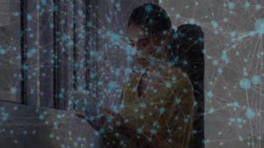 Tableti alan ve masadaki veri akışını analiz eden kadının etrafında görünen dijital ağ örtüsü. Teknoloji, yenilik, bağlantı, profesyonel, modern, çalışma alanı, veri